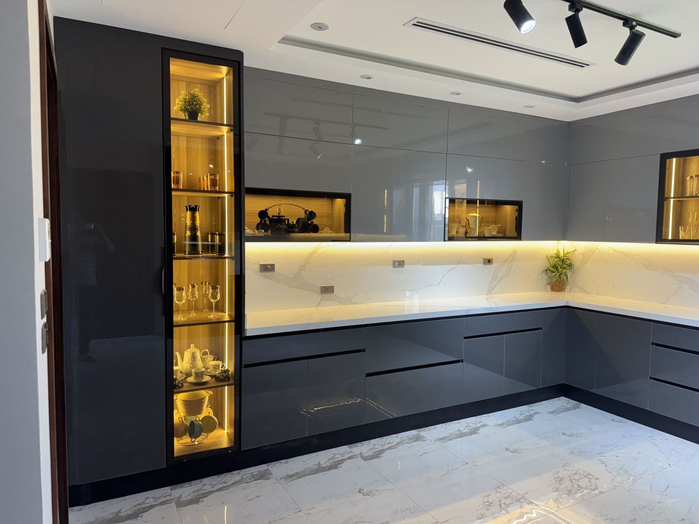 Dark gloss L-shaped kitchen with lit glass display cabinet