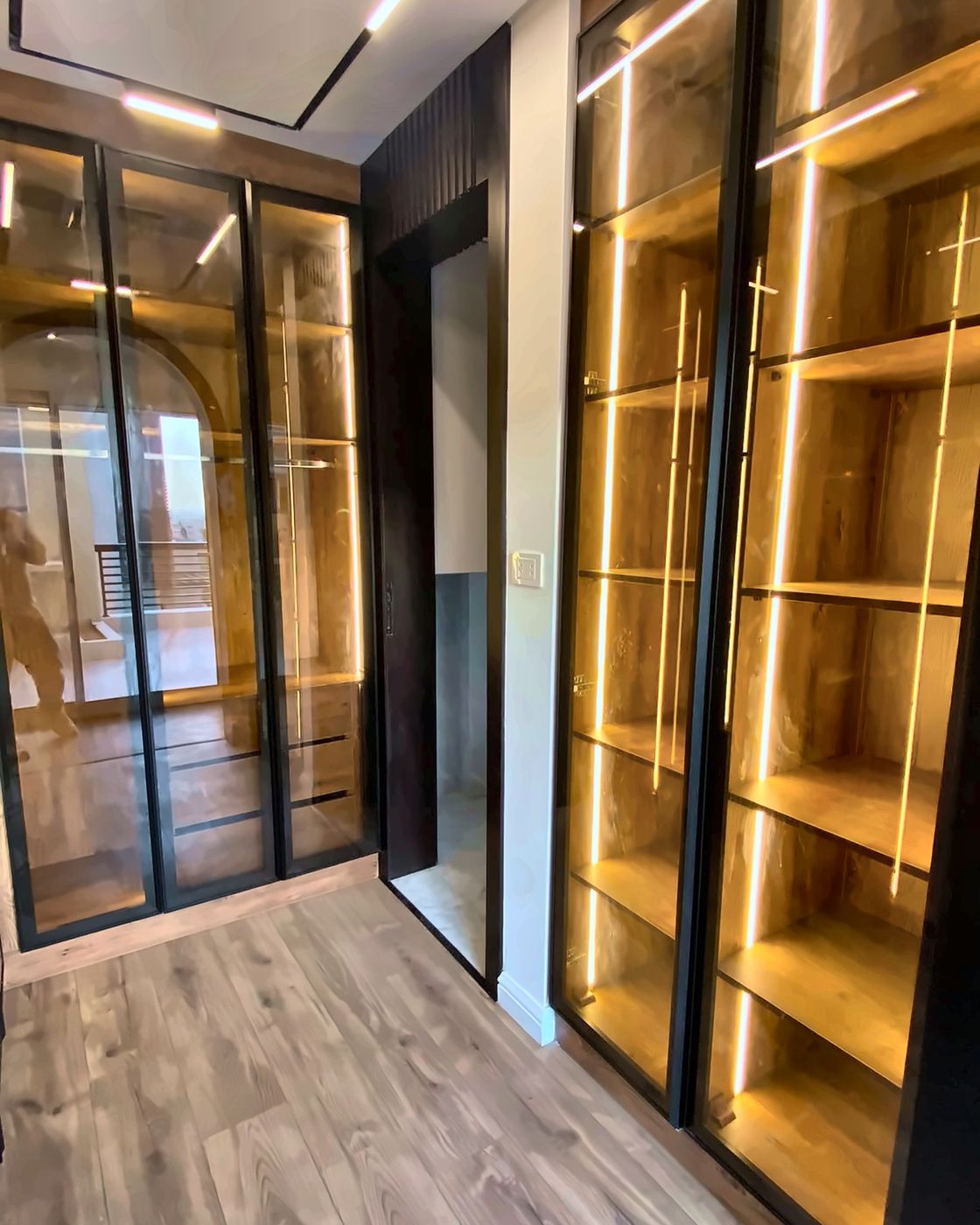 Lit open wooden shelves in a walk-in dressing room, New Giza